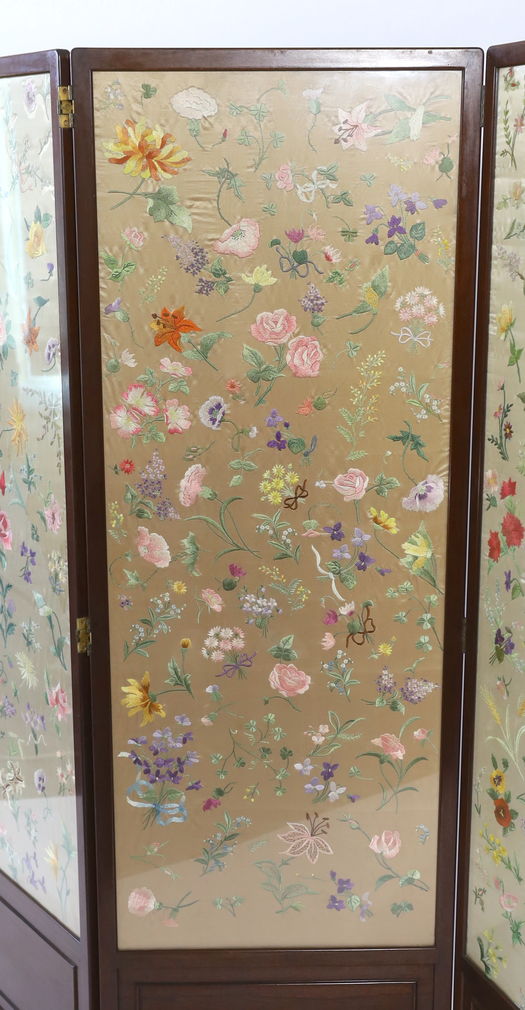 An Edwardian mahogany three fold screen with three panels of later (possibly 1920’s) hand embroidered, multi coloured, silk flowers, 50.5cm wide x 139cm high